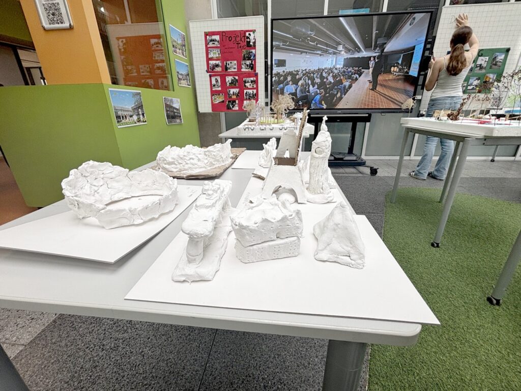 Tonmodelle von Colosseum, Elbphilharmonie,Eiffelturm etc.; im Hintergrund Bildschirm mit Doku von einer Veranstaltung