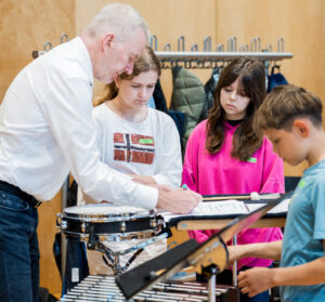 Schlagzeuger mit drei Kindern an Glockenspiel und kleiner Trommel