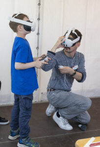 Zwei Jungen mit VR-Brillen. Der linke steht, der rechte hockt.